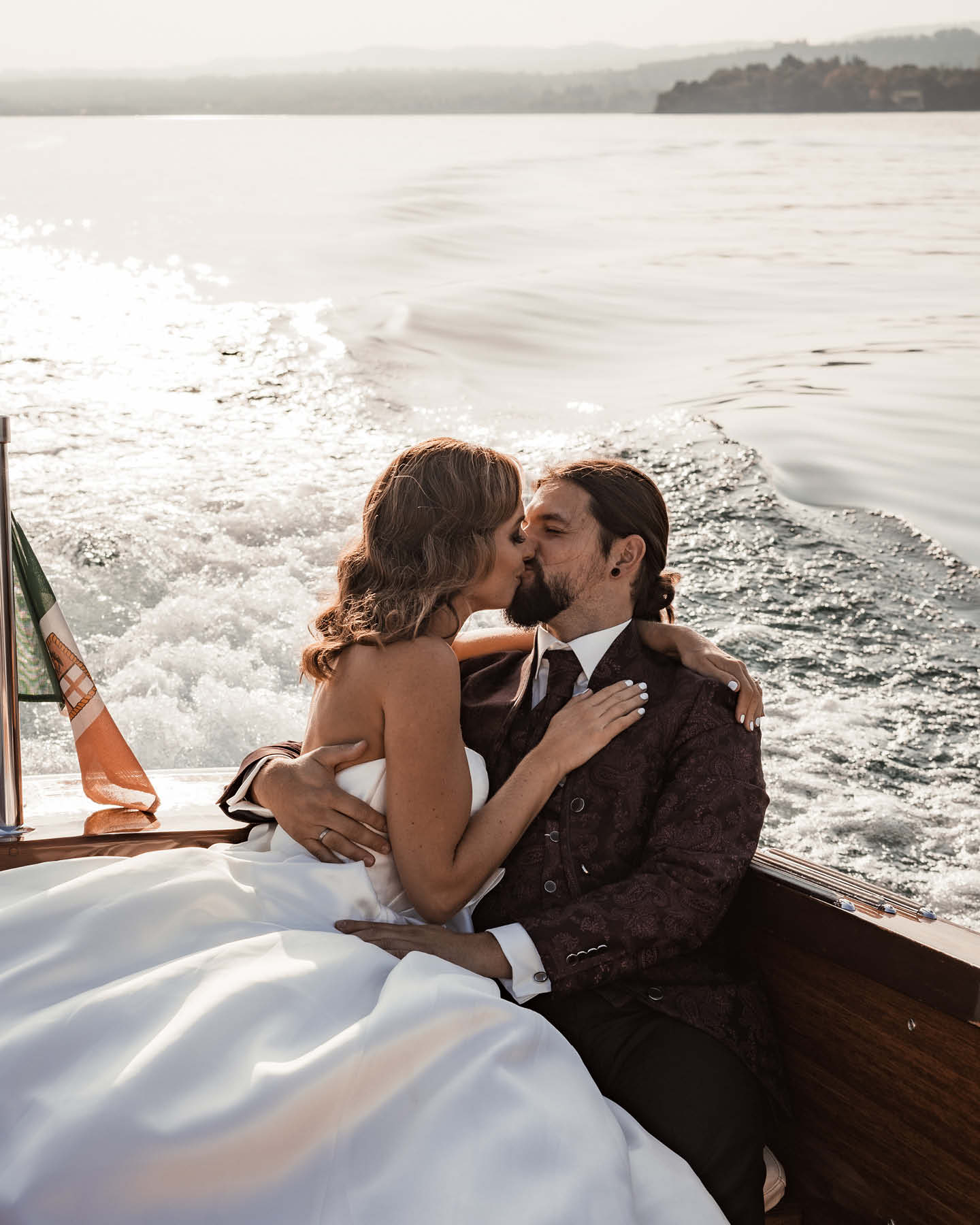 Ein Hochzeitspaar küsst sich auf einem Boot.