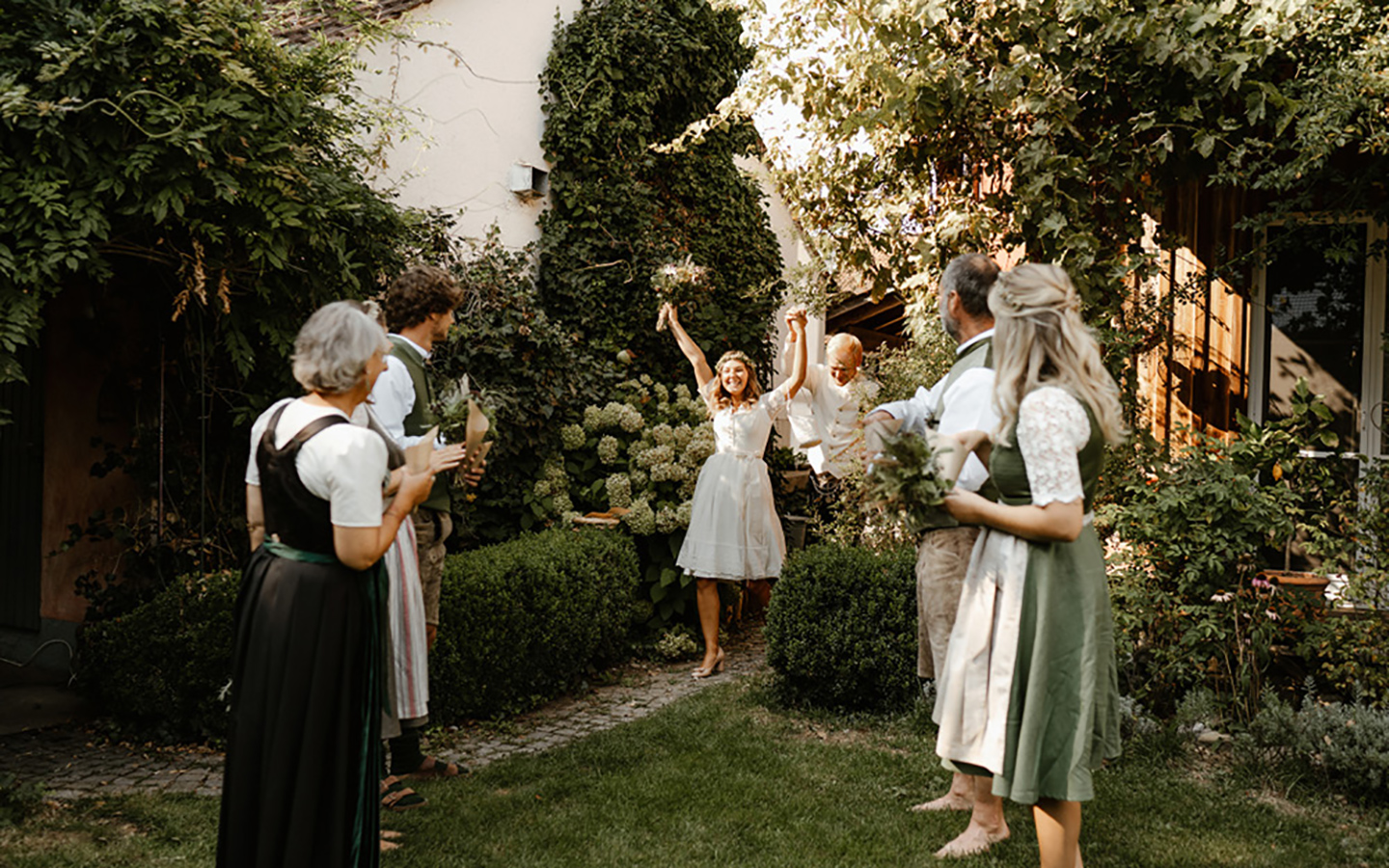 Die Braut und der Bäutigam kommen voller Freude in den Garten und werden von den Gästen freudig empfangen. 