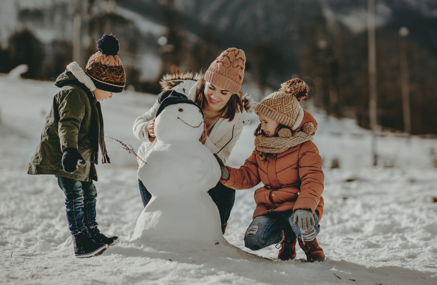 Winterfoto: Mutter baut Schneemann mit Kindern