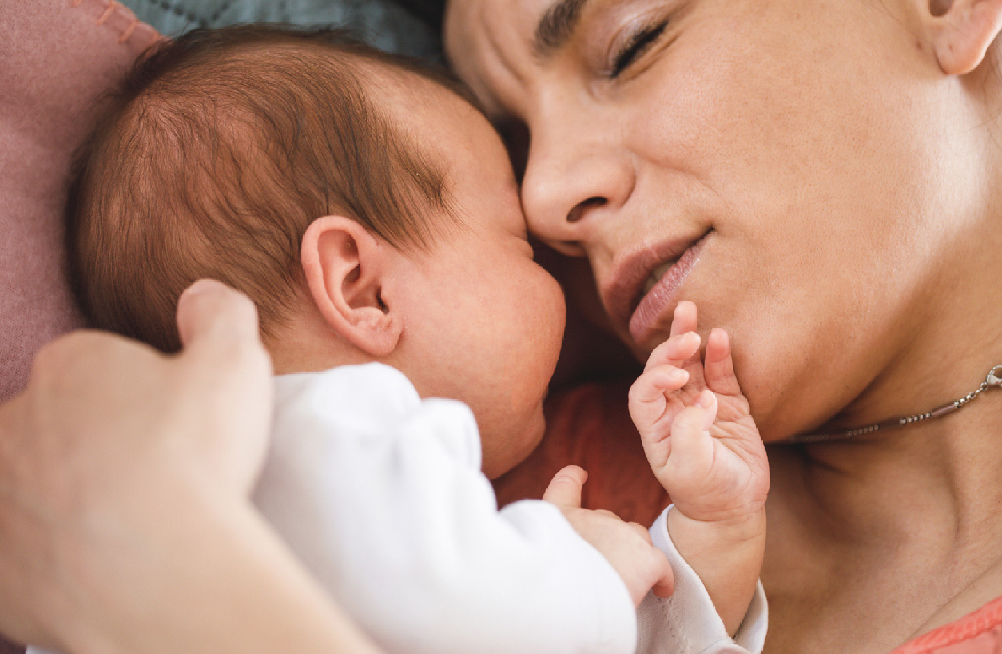 Mutter kuschelt mit geschlossenen Augen mit ihrem schlafenden Baby