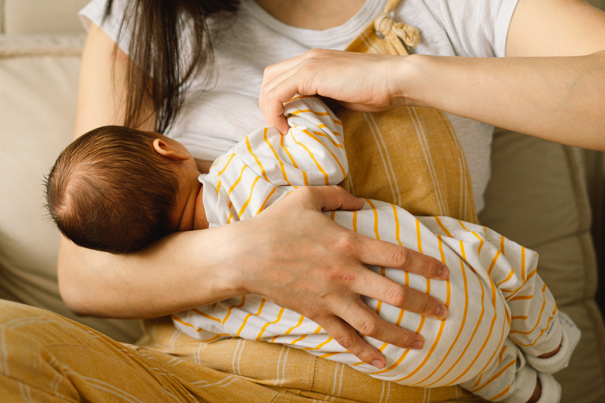 Eine Mama hat ihr Baby auf dem Arm und stillt es.