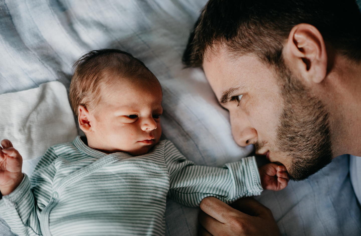 Vater kuschelt mit Baby im Bett