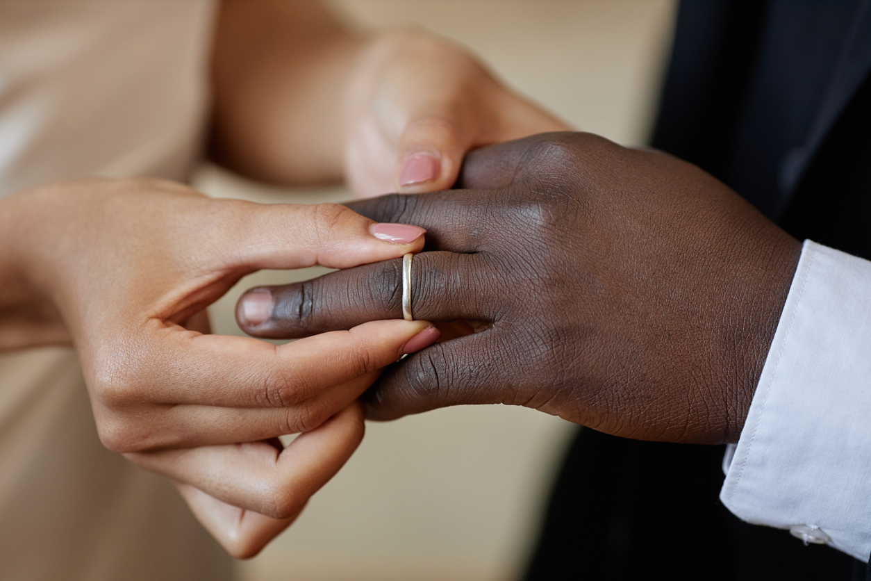 Frau steckt Ehering an den Finger ihres Mannes