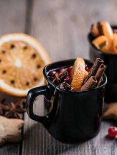 Zwei Tassen mit Feuerzangenbowle stehen auf einem Holztisch.