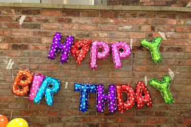 Ballons an einer Wand die "Happy Birthday" darstellen