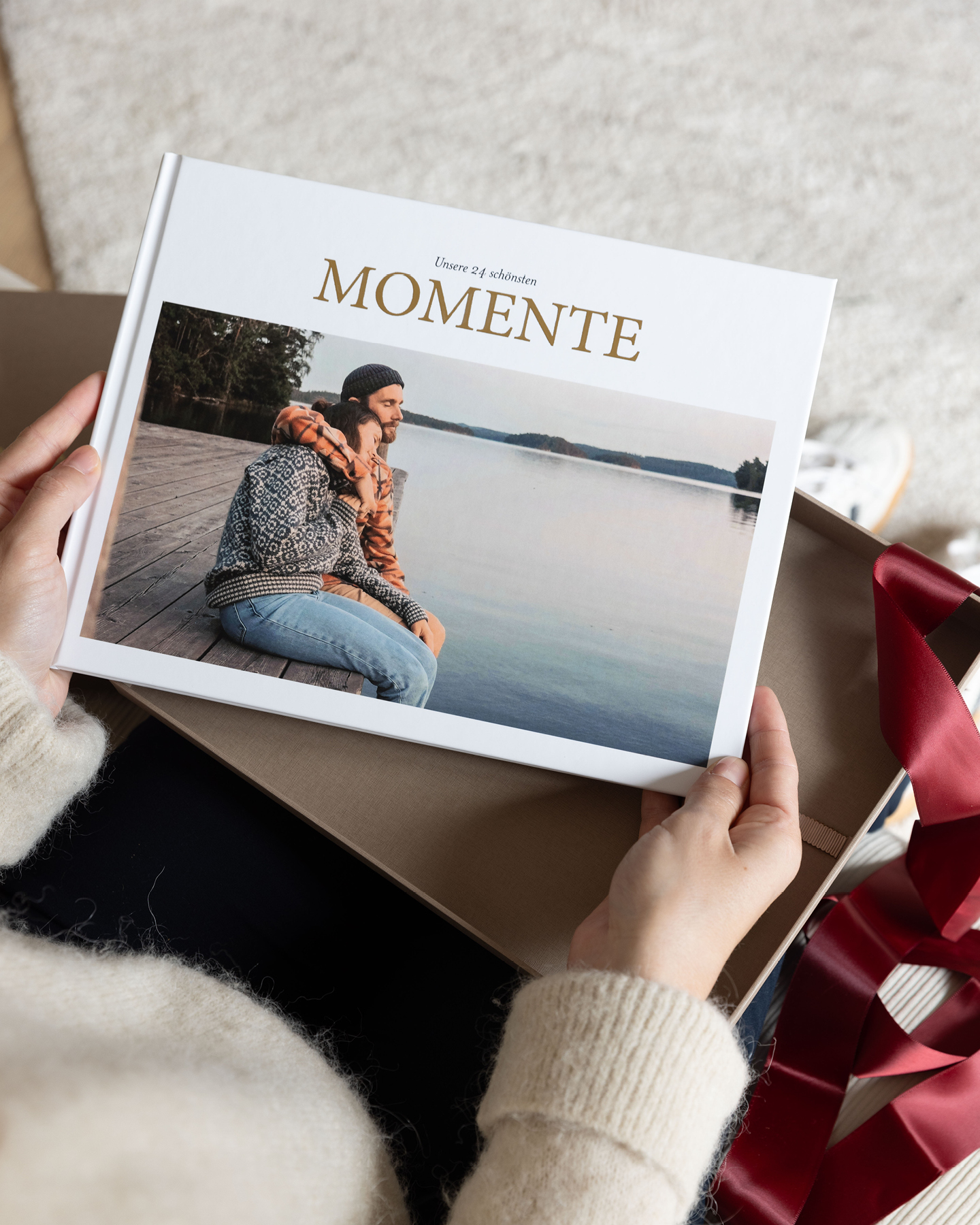 Frau (nicht im Bild) entnimmt Fotobuch-Adventskalender aus Geschenkbox