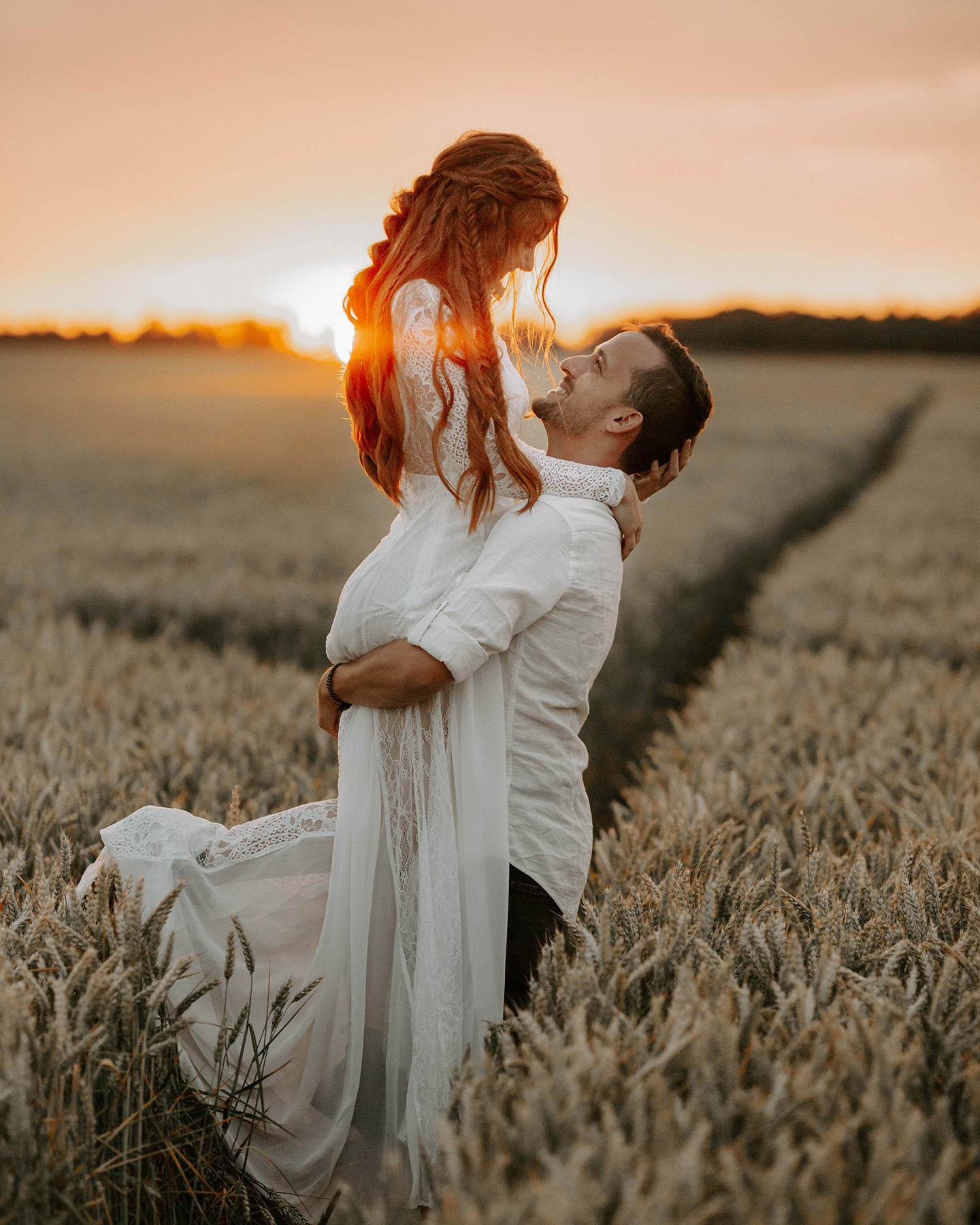 Brautpaar wird in romantischer Stimmung bei Abendsonne im Kornfeld fotografiert