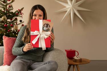 Frau hält Geschenk vor sich.