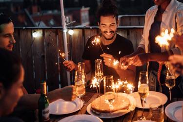 Freunde in den Dreißigern bei einer kleinen abendlichen Geburtstagsparty auf dem Balkon