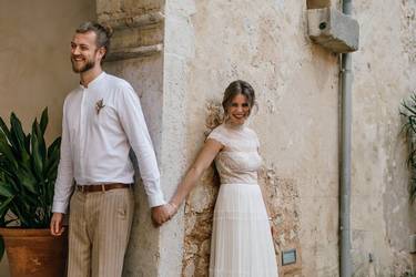 Hochzeitspaar an einer Mauer stehend umgeben von einem mediterrane Flair.