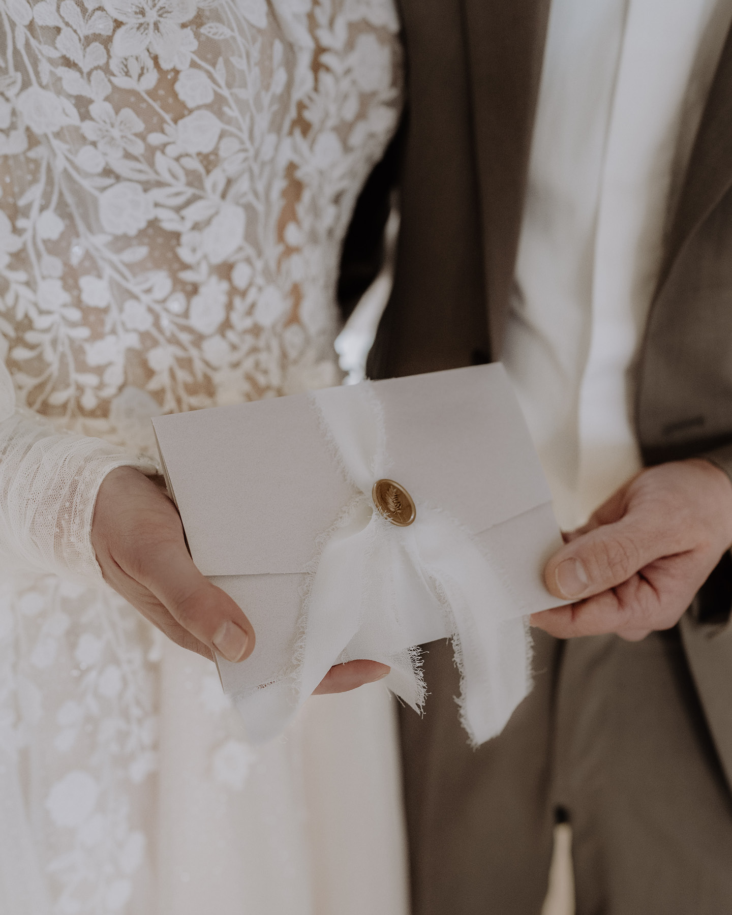 Hochzeitspaar hält mit Schleife und Siegel vrziete Hochzeitseinladung in der Hand