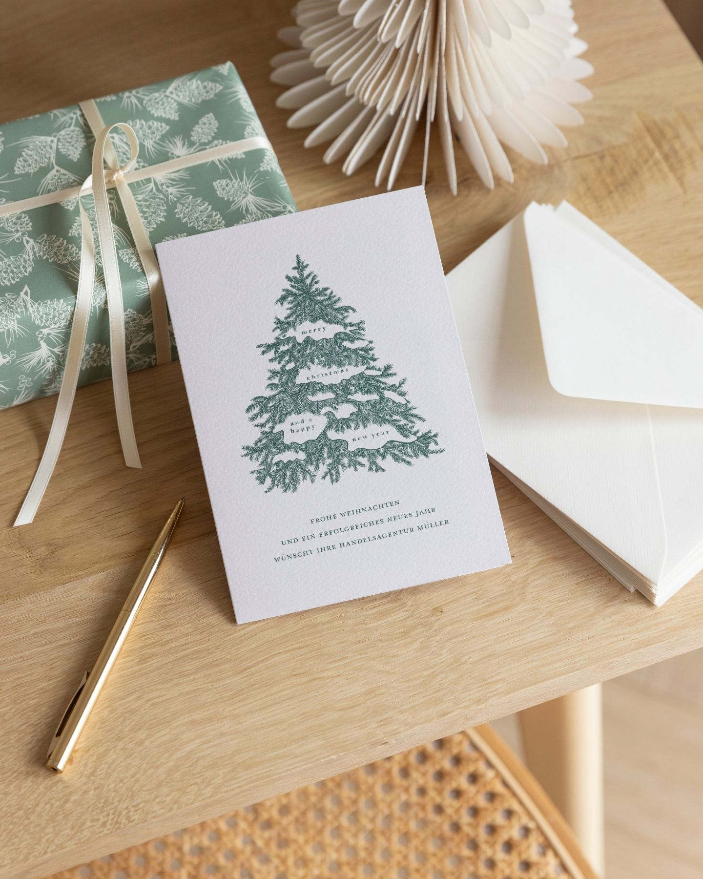 Geschäftliche Weihnachtskarte mit Stift,Umschlägen, Geschenk und Origami-Deko auf einem Tisch