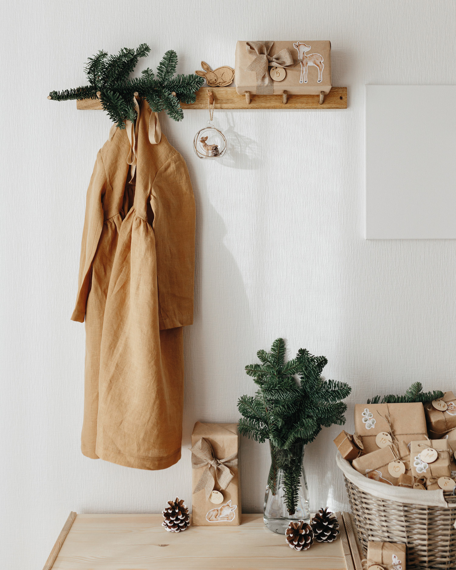 Adventskalender füllen: Kleine Pakete in Kraftpapier verpackt liegen mit Tannengrün in einem Korb.