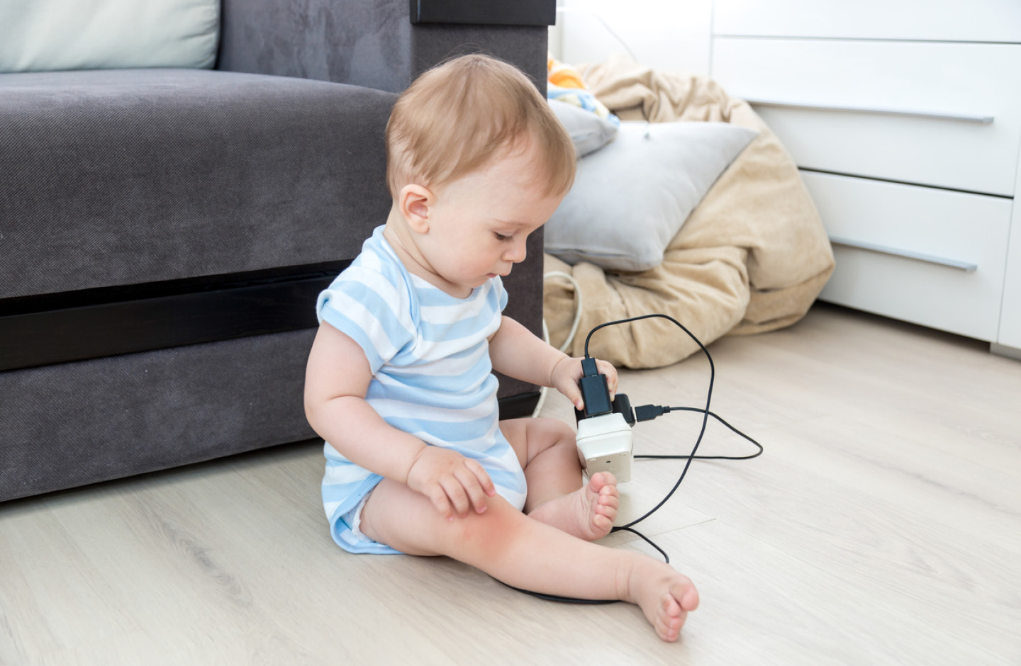 Baby sitzt auf dem Boden und spielt mit Mehrfachsteckdose