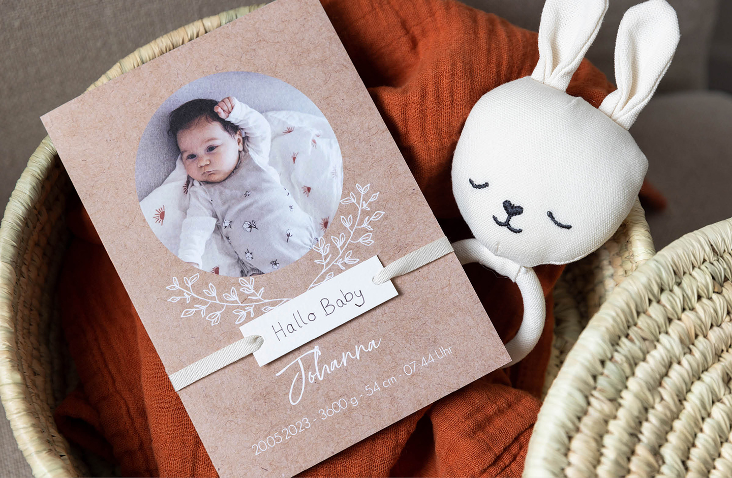 Geburtskarte mit "Hallo Baby" Anhänger liegt in Korb. Geburtskarte basteln.