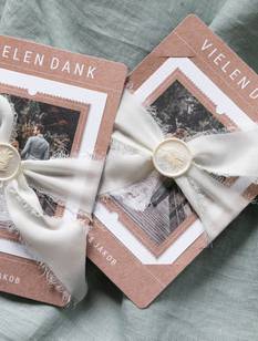 Zwei Hochzeits-Dankeskarten mit Siegel und beigem Seidenband umwickelt.