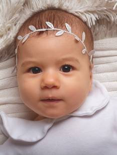 Baby in Weiß gekleidet mit weißer Ranke als Kopfschmuck