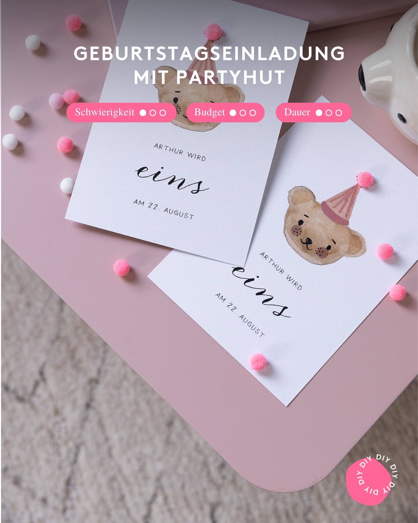 Einladungskarte zum 1. Geburtstag mit Bär-Illustration liegt auf einem rosa Umschlag