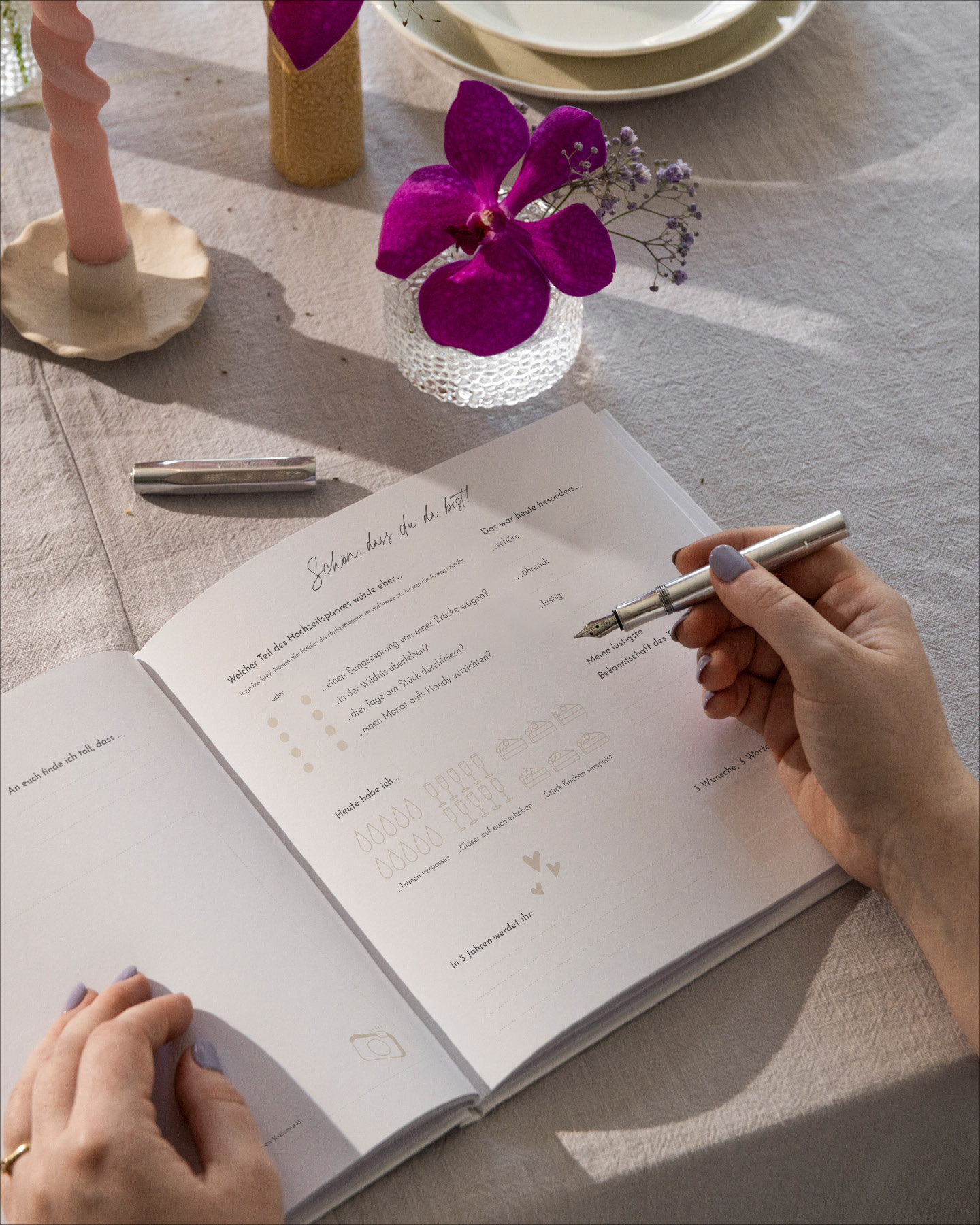 Aufgeklapptes Hochzeitsgästebuch auf einem Tisch, weibliche Hände mit Stift