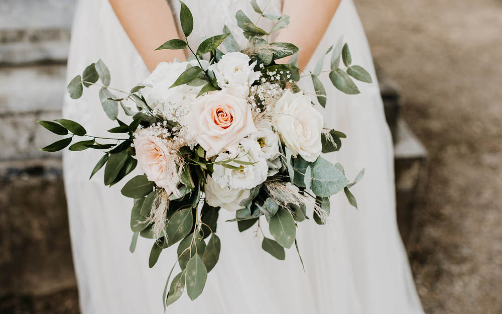 Braustrauß mit grünen Blättern und weißen Rosen.