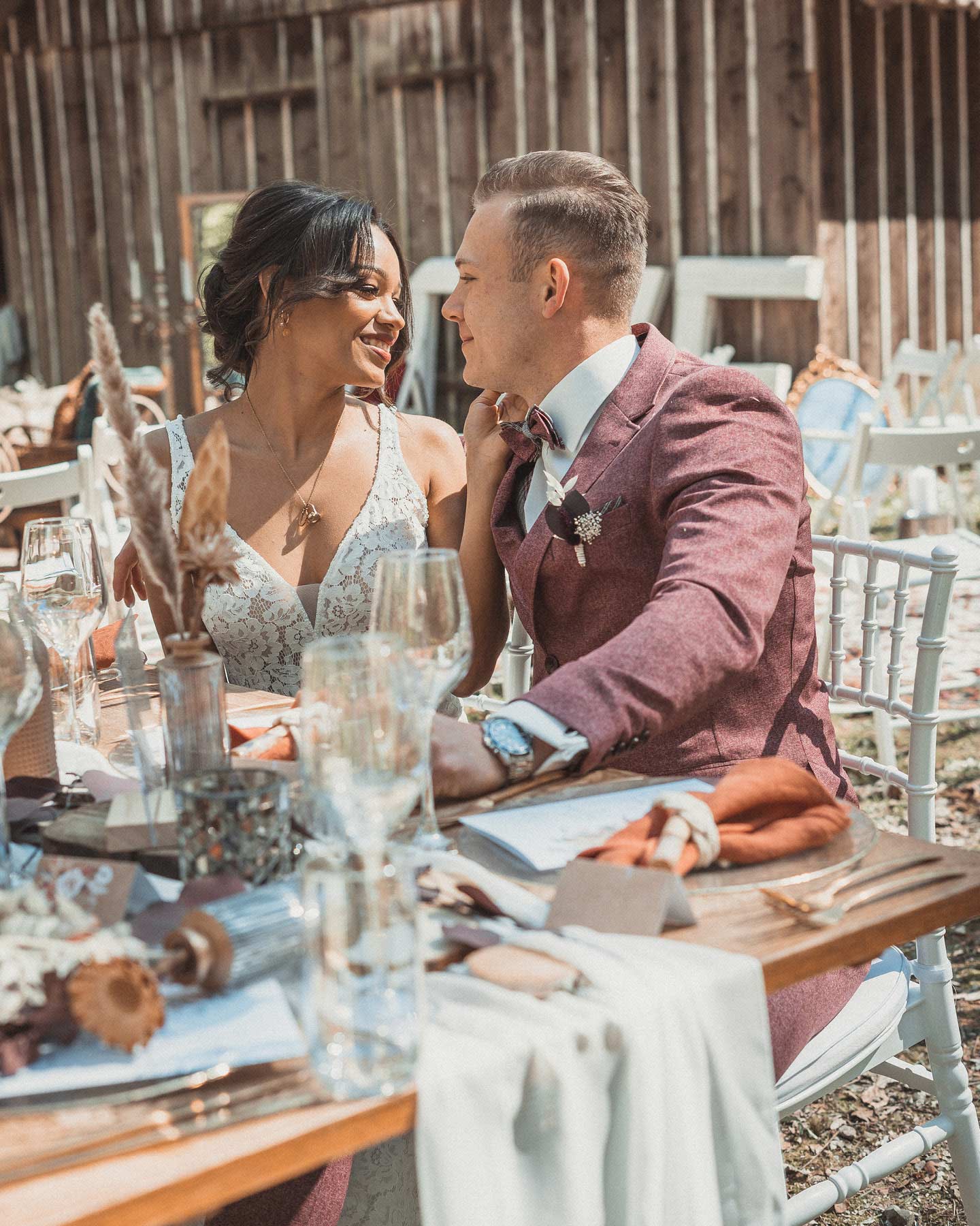 Boho Vintage Brautpaar sitzt an der Hochzeitstafel in Erdtönen.