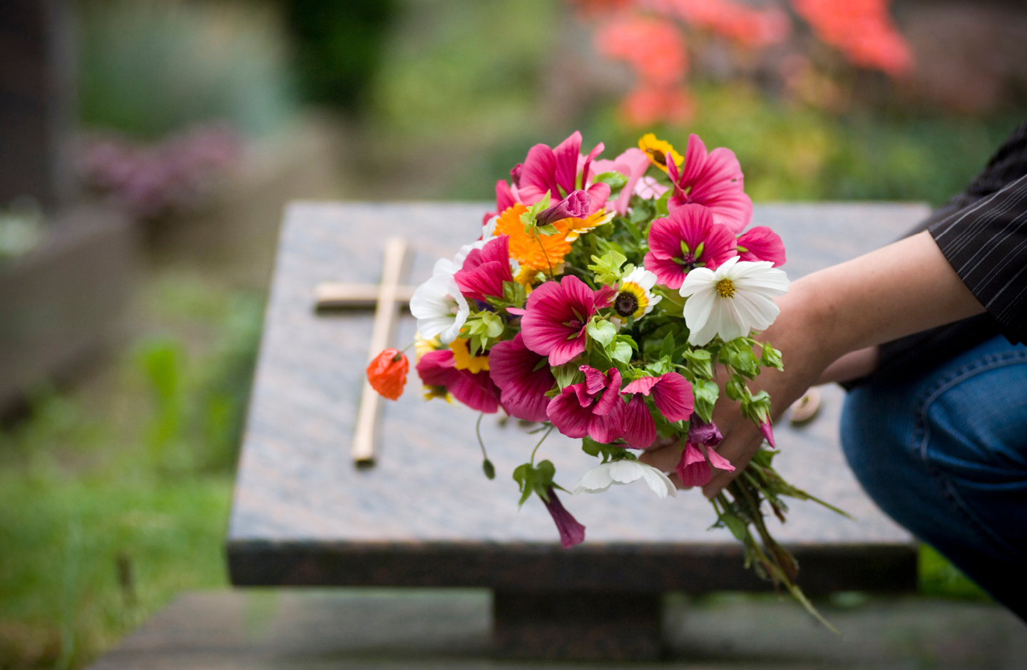 Frau legt nach dem Trauergottesdienst Blumen am Grab ab.