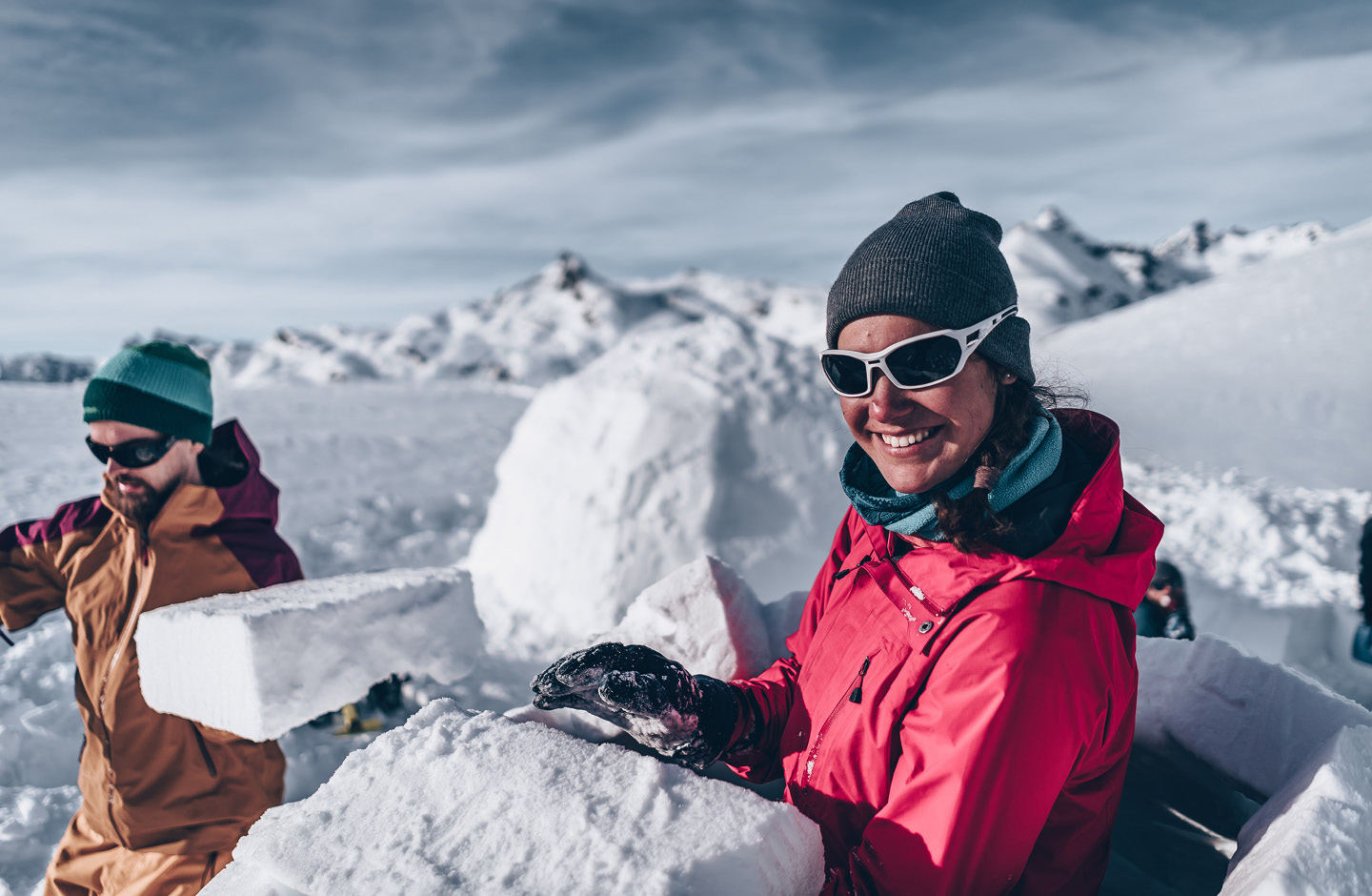 Mann und Frau bauen ein Iglu aus Schneeblöcken