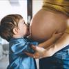 Kleiner JungE umarmt Babybauch seiner Mutter