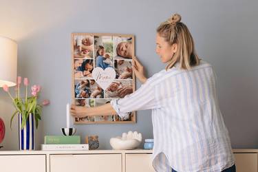 Junge Mutter hängt ihr Muttertagsgeschenk, eine gerahmte Cllage, an die Wand