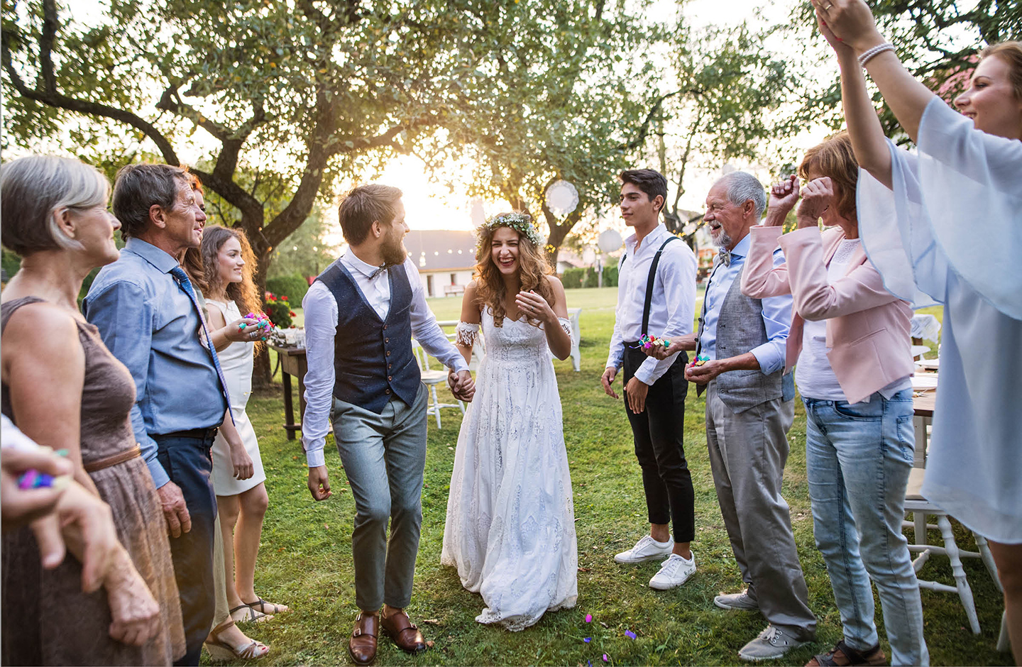 Hochzeitsgäste empfangen das Brautpaar im Garten der Location.