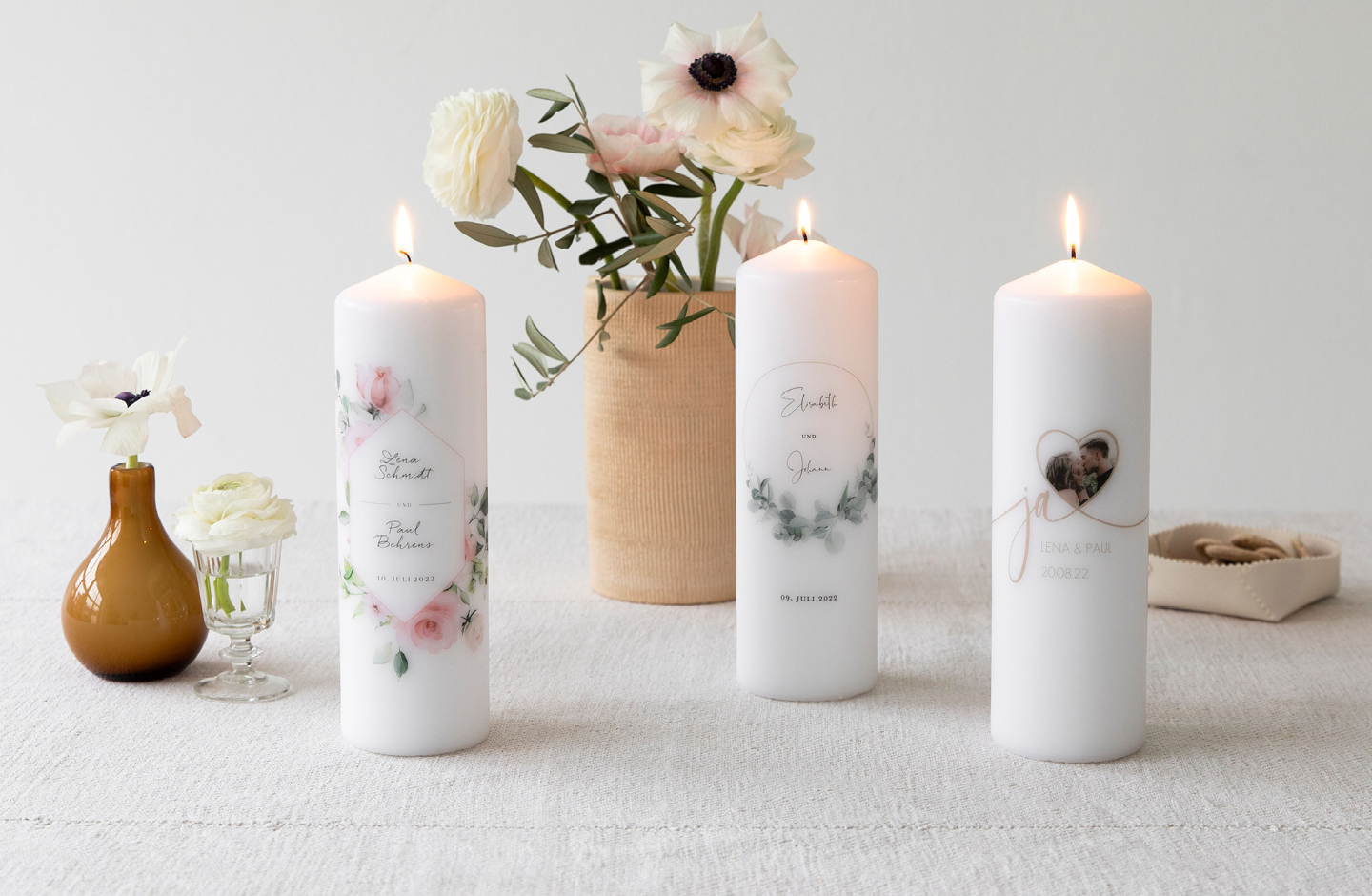 3 verschiedene Hochzeitskerzen mit Vasen arrangiert