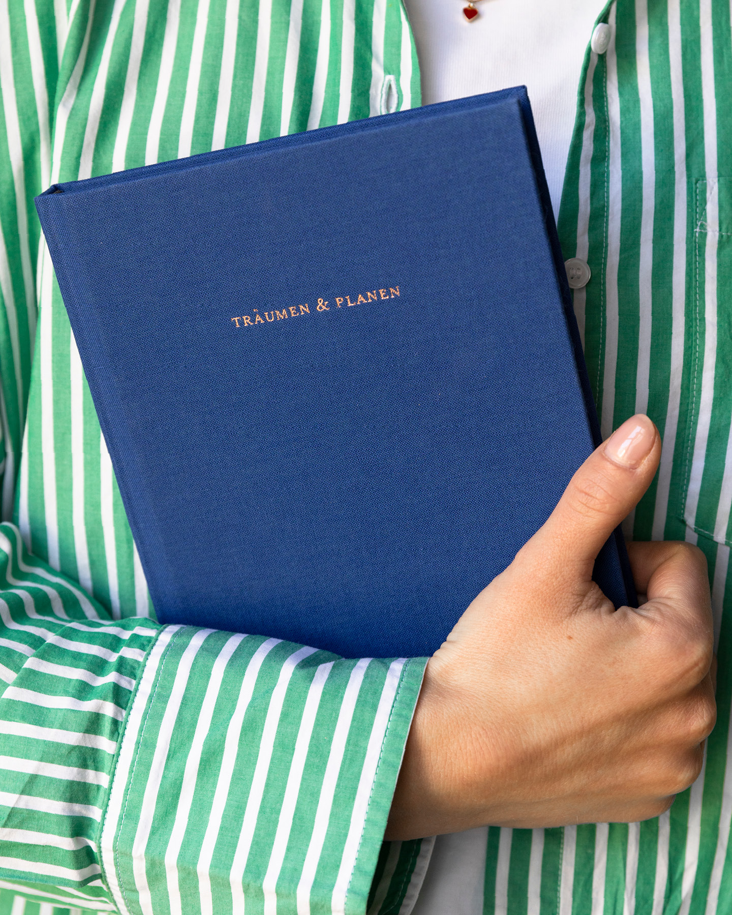 Bildausschnitt: Junge Mitter mit ihremMuttertagsgeschenk im Arm, einem personalisierten Notizbuch