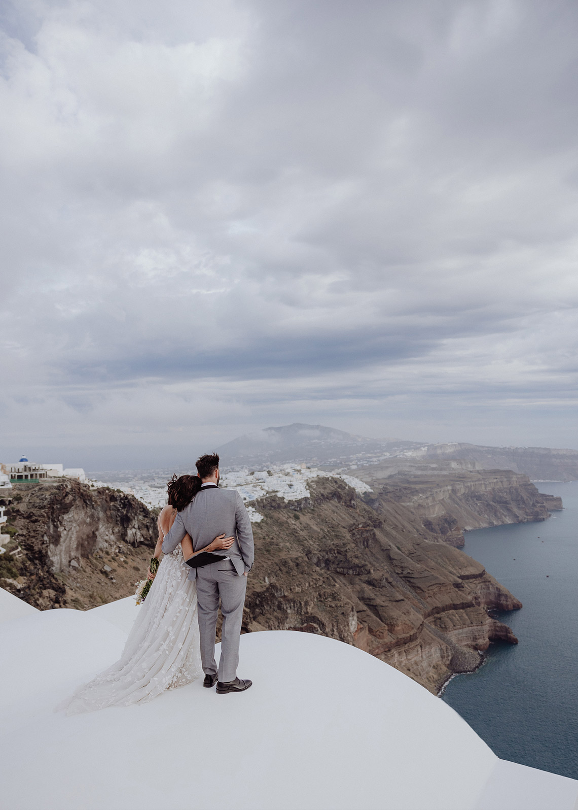 Das Brautpaar genießt den Ausblick auf die Küste Santorinis von einer Kirche aus