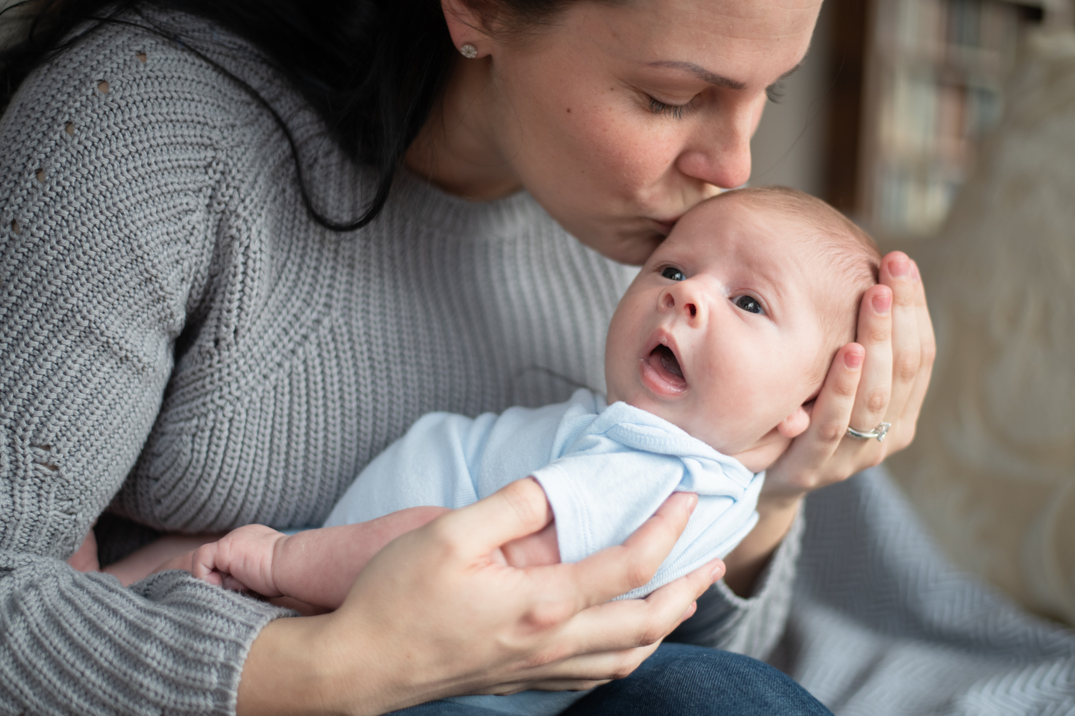 Mutter hält Baby im Ar und küsst es aufs Köpfchen