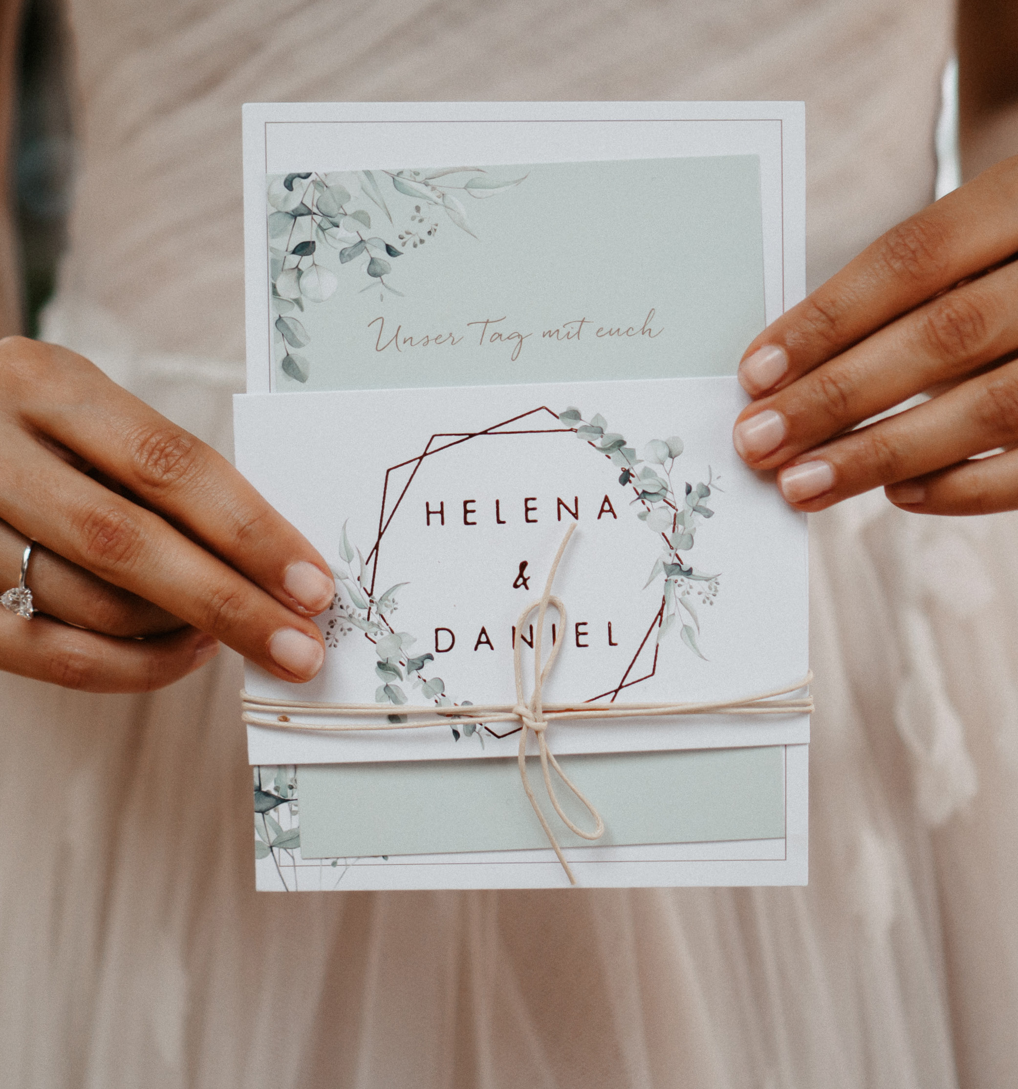 Hochzeitseinladung "Soft Greenery" als Kartenset mit Eukalyptus Zeichnung wird von der Braut gehalten.