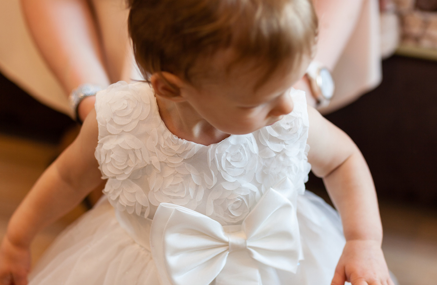 kleines Mädchen im Taufkleid mit großer, aufgesetzter Schleife