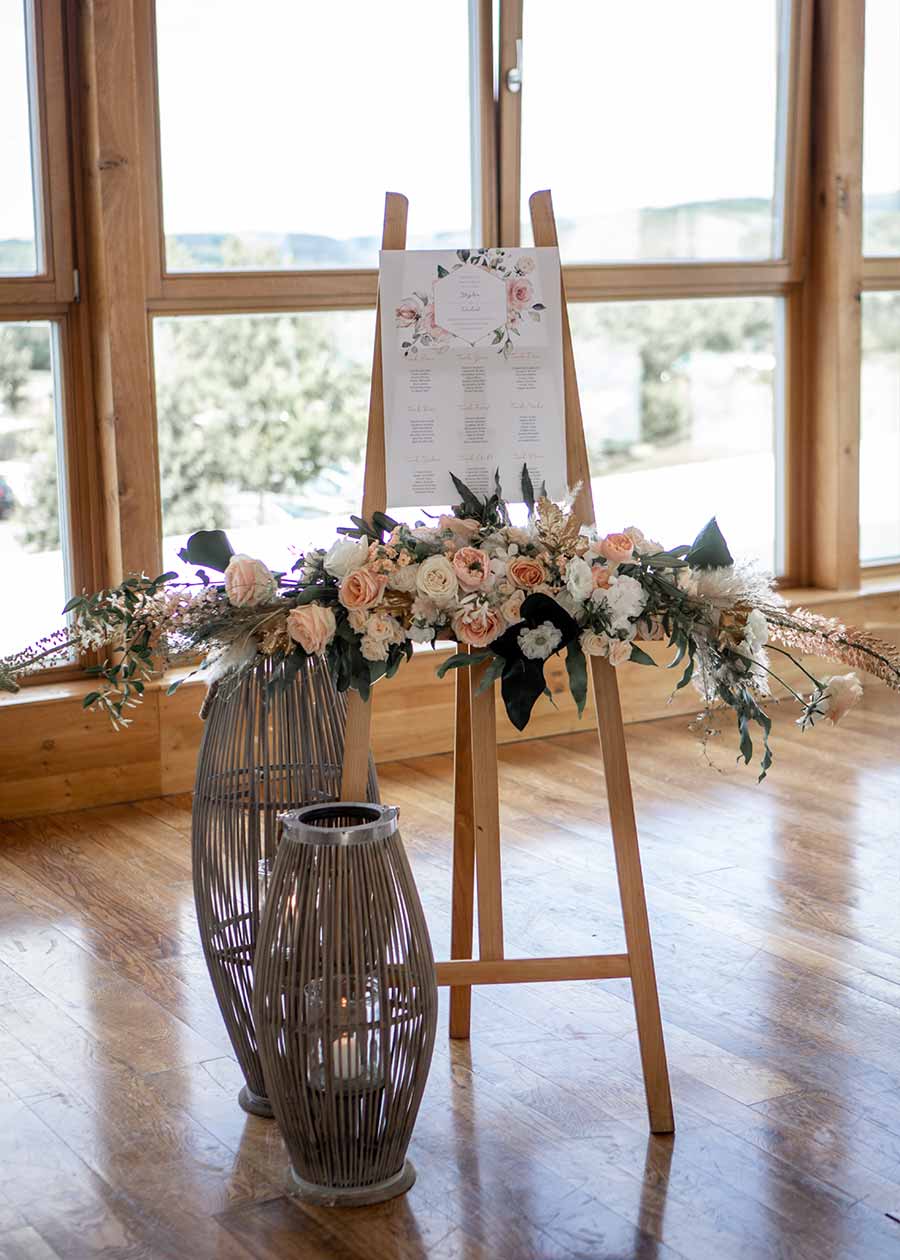 DIY Idee: Der Sitzplan steht auf einer Holzstaffelei und ist dekoriert mit einem Blumenbouquet.