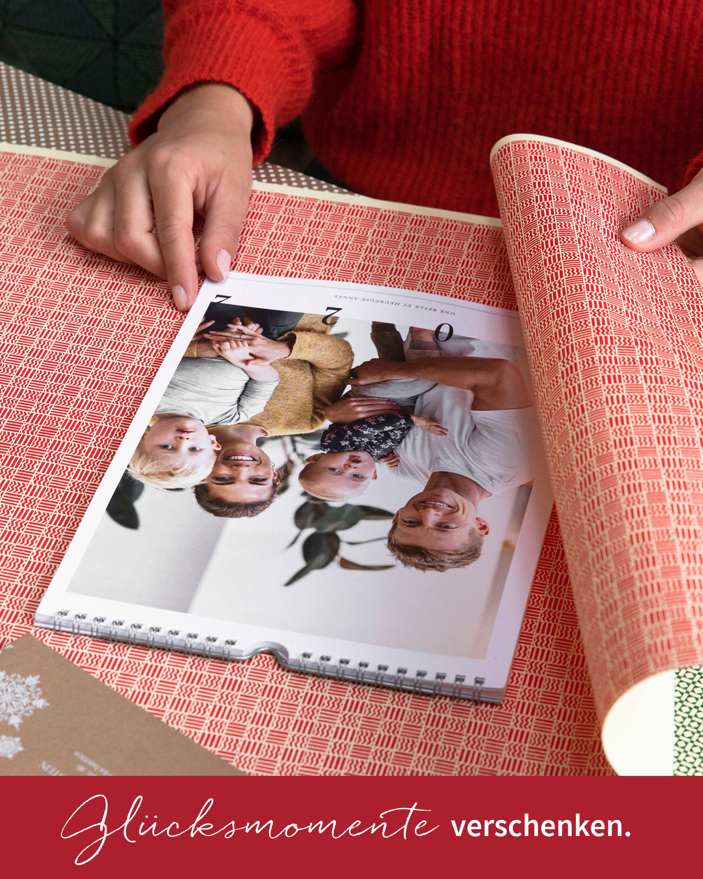 Fotokalender für die Wand wird mit bunten Geschenkpapier zu Weihnachten eingepackt.