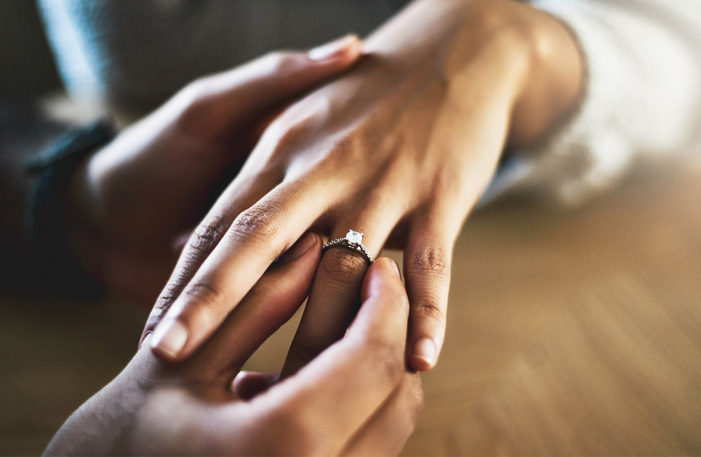 Detailaufnahme von zwei Händen, wie der Mann der Frau einen Ring and den Finger steckt. 