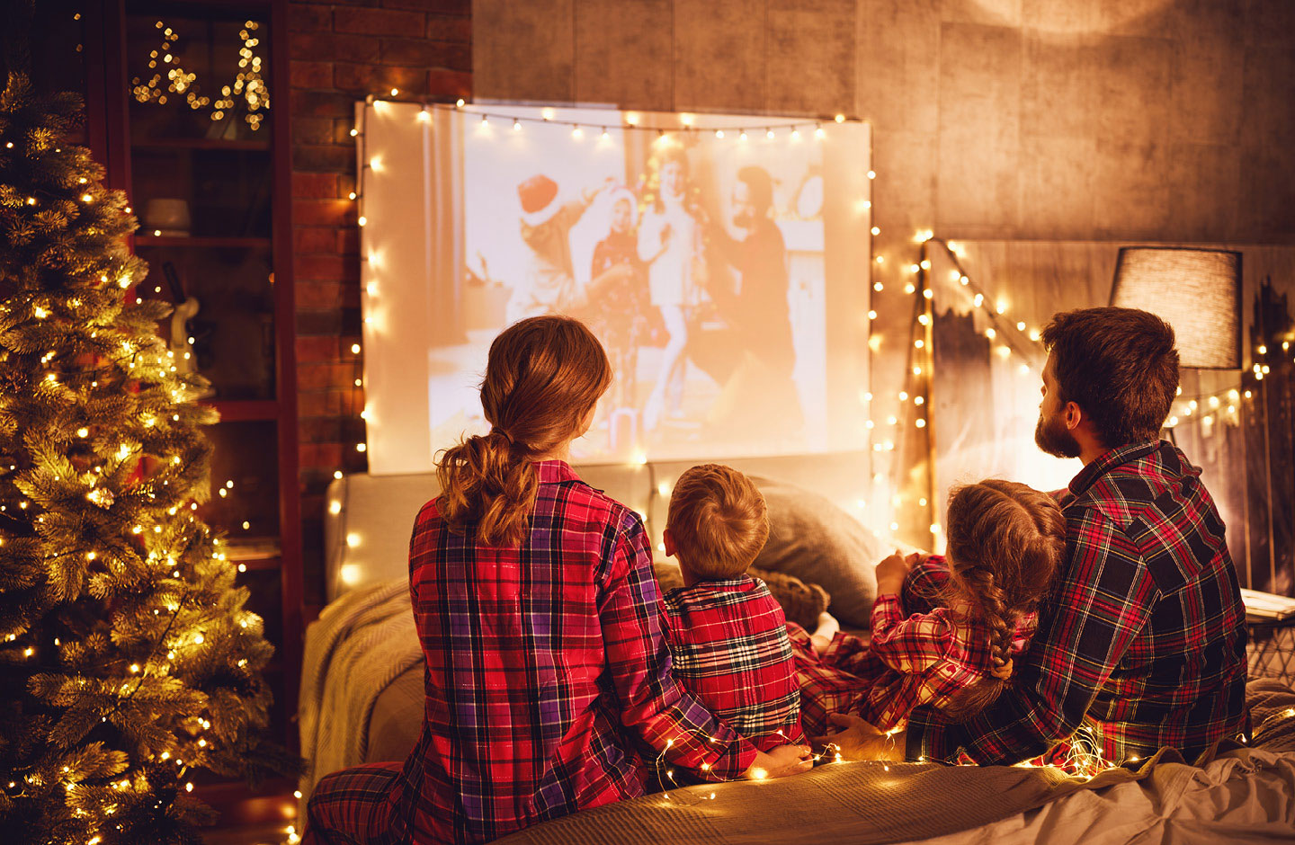 Familie guckt zusammen zuhause auf einer Leinwand einen Weihnachtsfilm.
