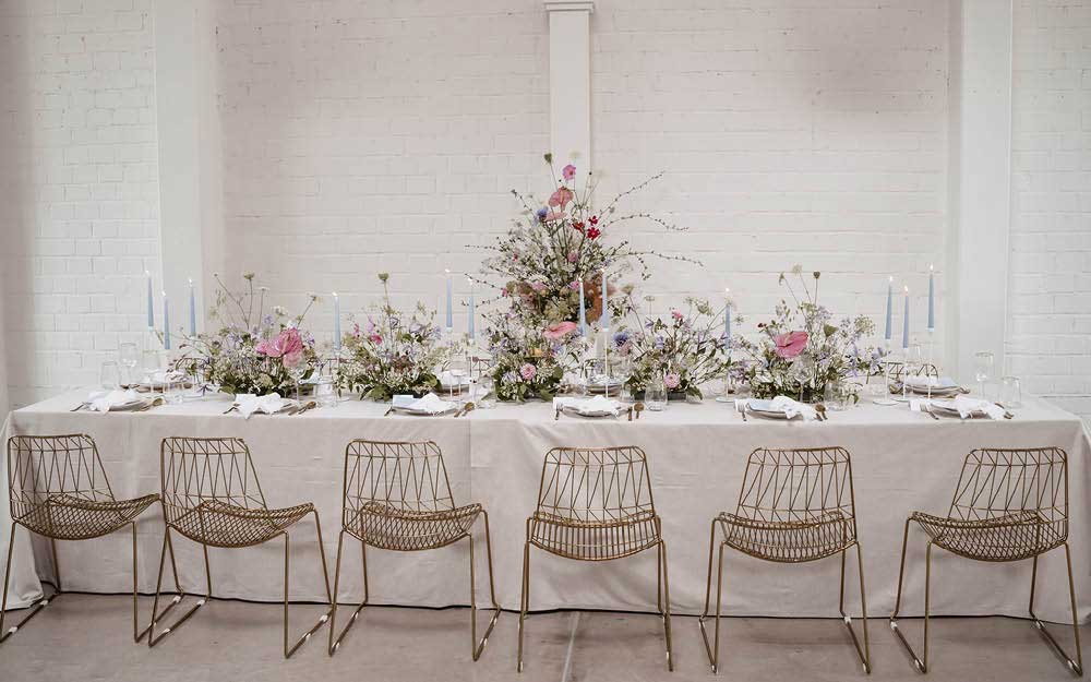 Floral Chic Wedding Hochzeitstafel: Blumenbouquets mit zarten Blüten und violette Kerzen schmücken den Tisch mit weißer Tischdecke