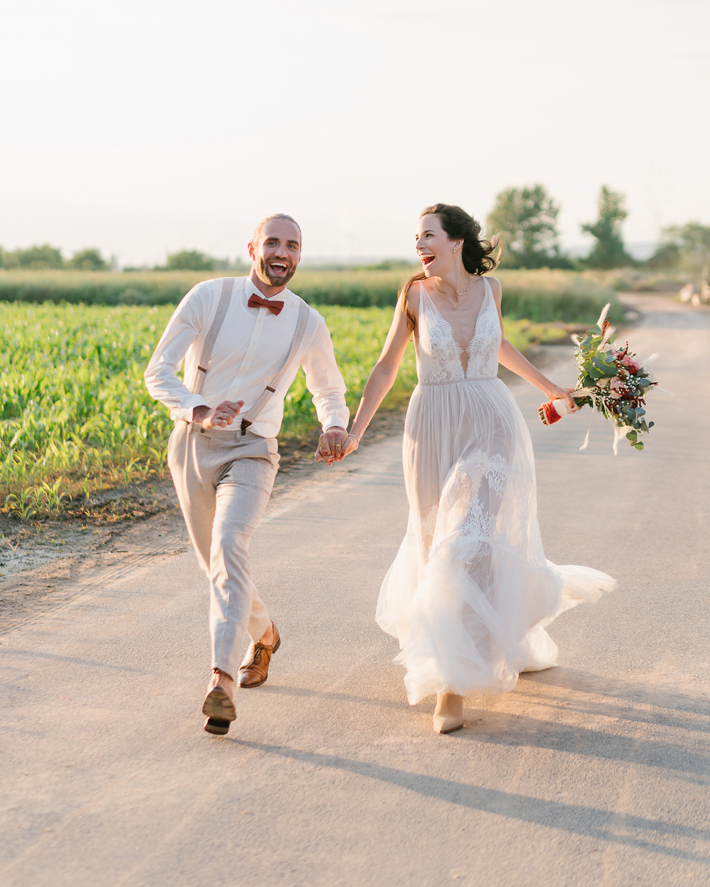 Lachendes Hochzeitspaar läuft auf einer ländlichen Straße