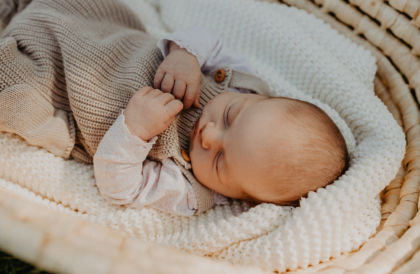 Schlafendes Baby in Babykorb mit Strickdecke 