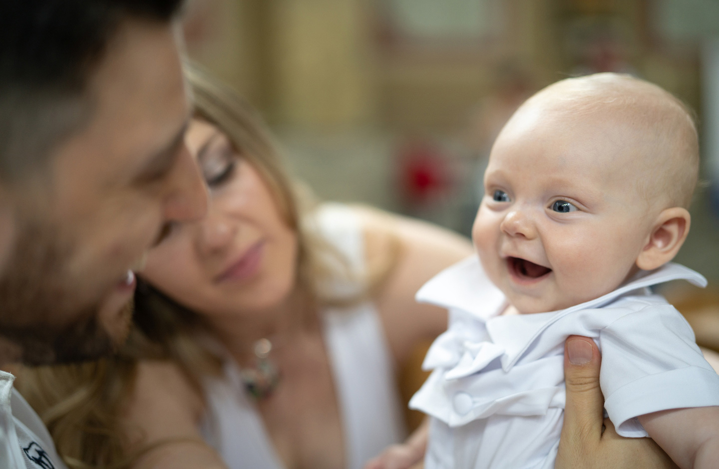 Lachendes Baby mit den Eltern bei der Taufe