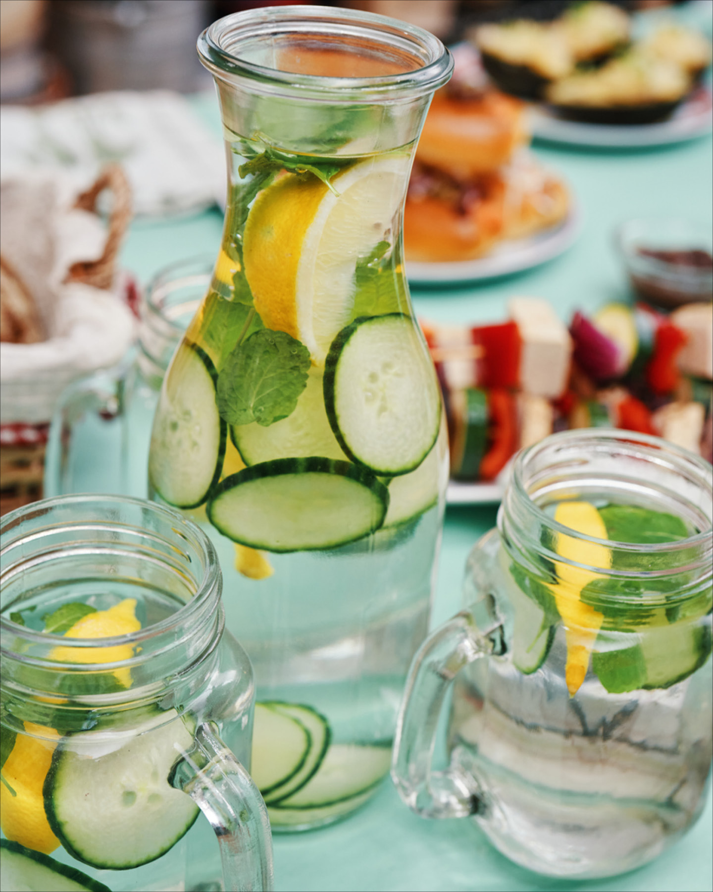 Karaffe und Gläser mit Wasser, Gurken, Zitronen und Minze