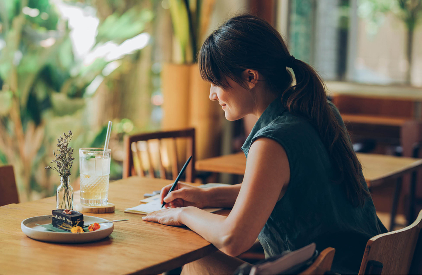 Eine Frau sitzt am Tisch und schreibt einen Brief. 