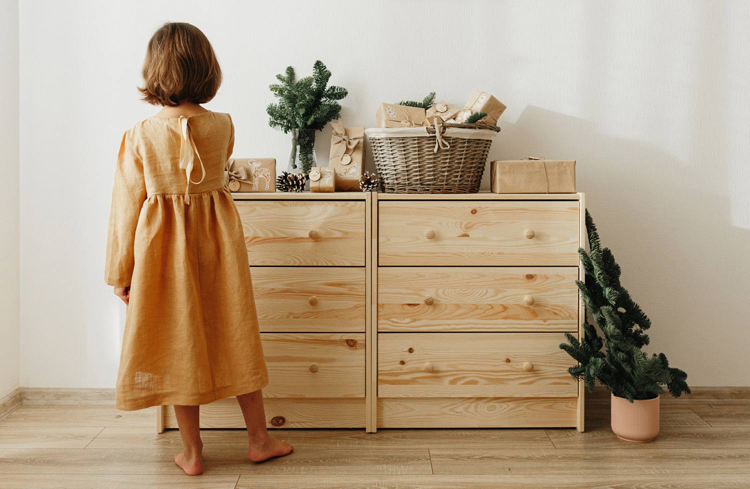 Kleines Mädchen steht vor Holzkommode und betrachtet ihren Adventskalender