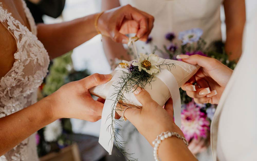 Braut löst Ehering von weißem Ringkissen