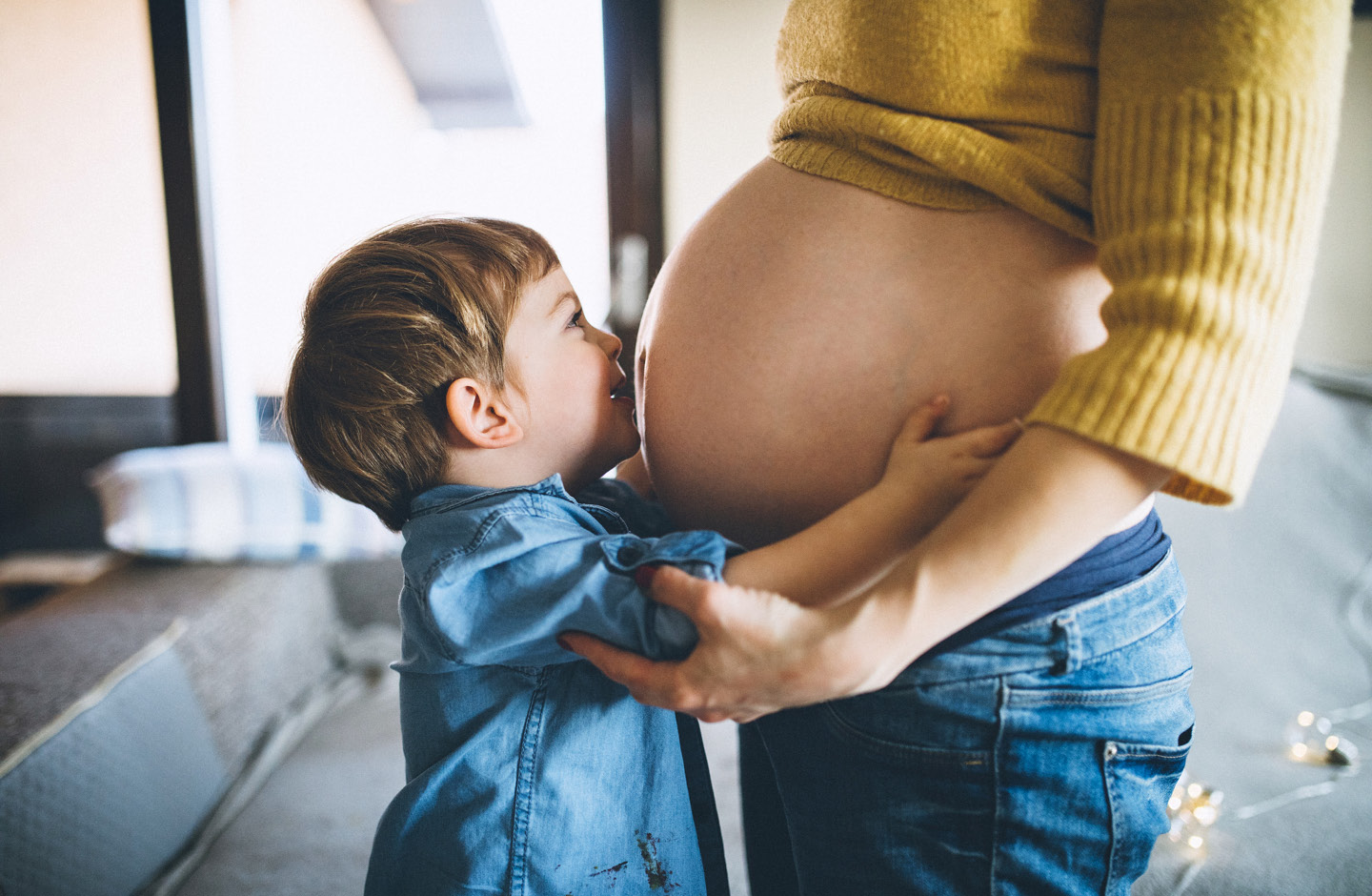 Kleiner Junge umarmt Bauch seiner schwangeren Mutter