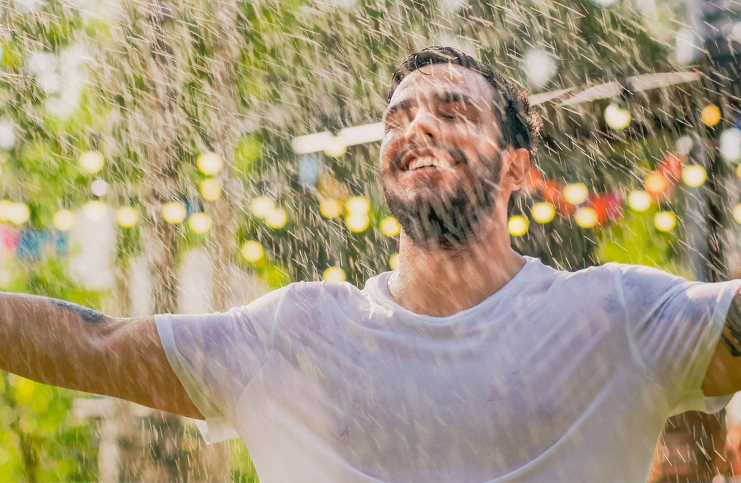 Mann tanzt bei Regen im Garten.